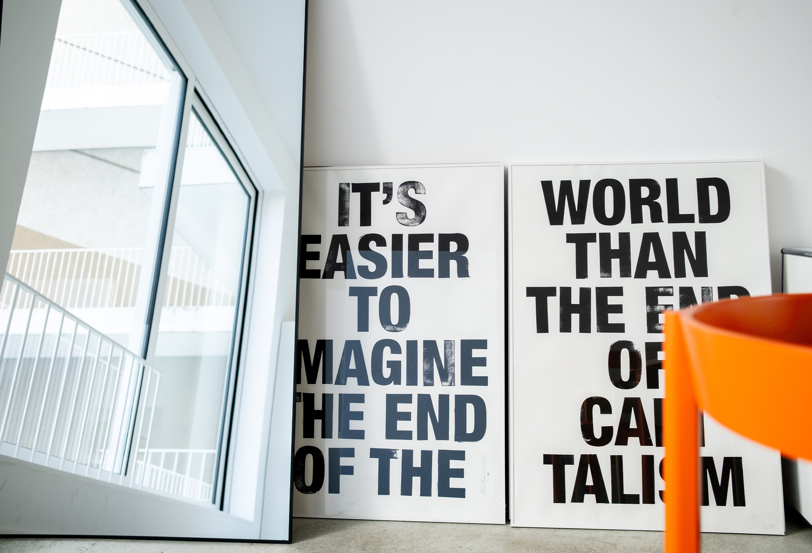 Two large letterpress-style prints leaning against the studio wall, beside a full-length mirror reflecting the studio windows
