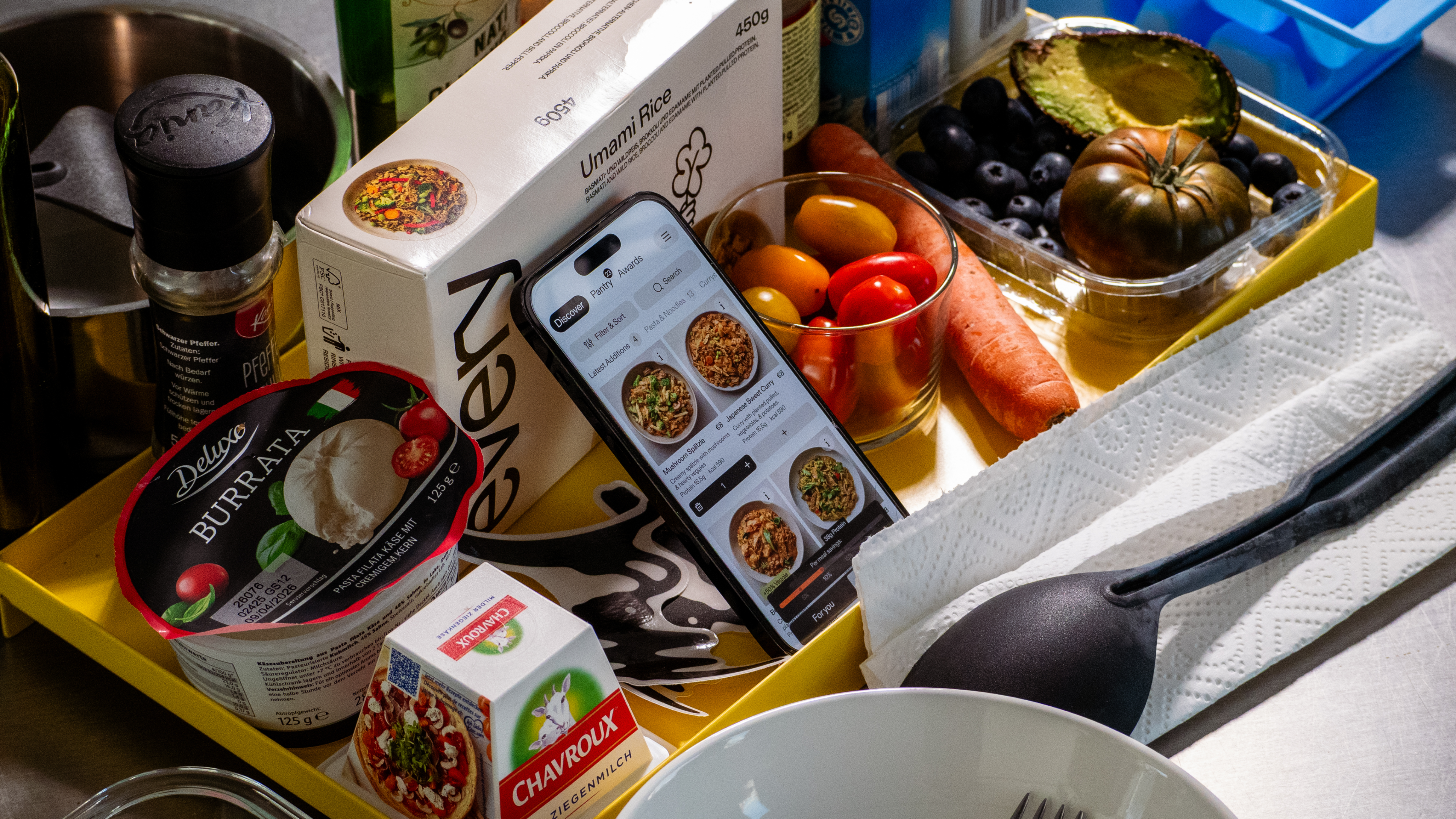 Every Foods app on an iPhone propped among fresh ingredients on a kitchen counter