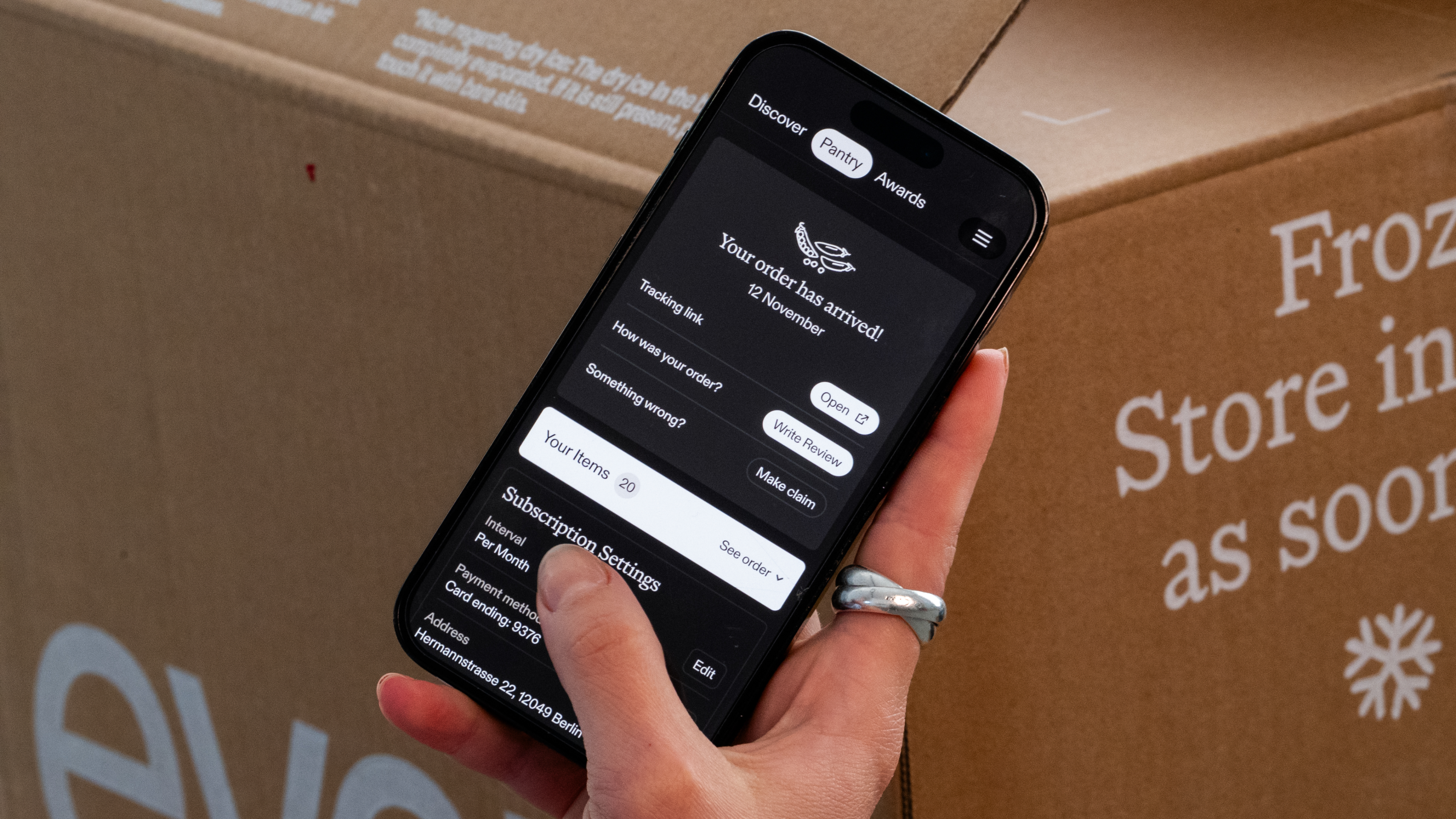 Hand holding a phone showing the Every app "Your order has arrived!" confirmation screen