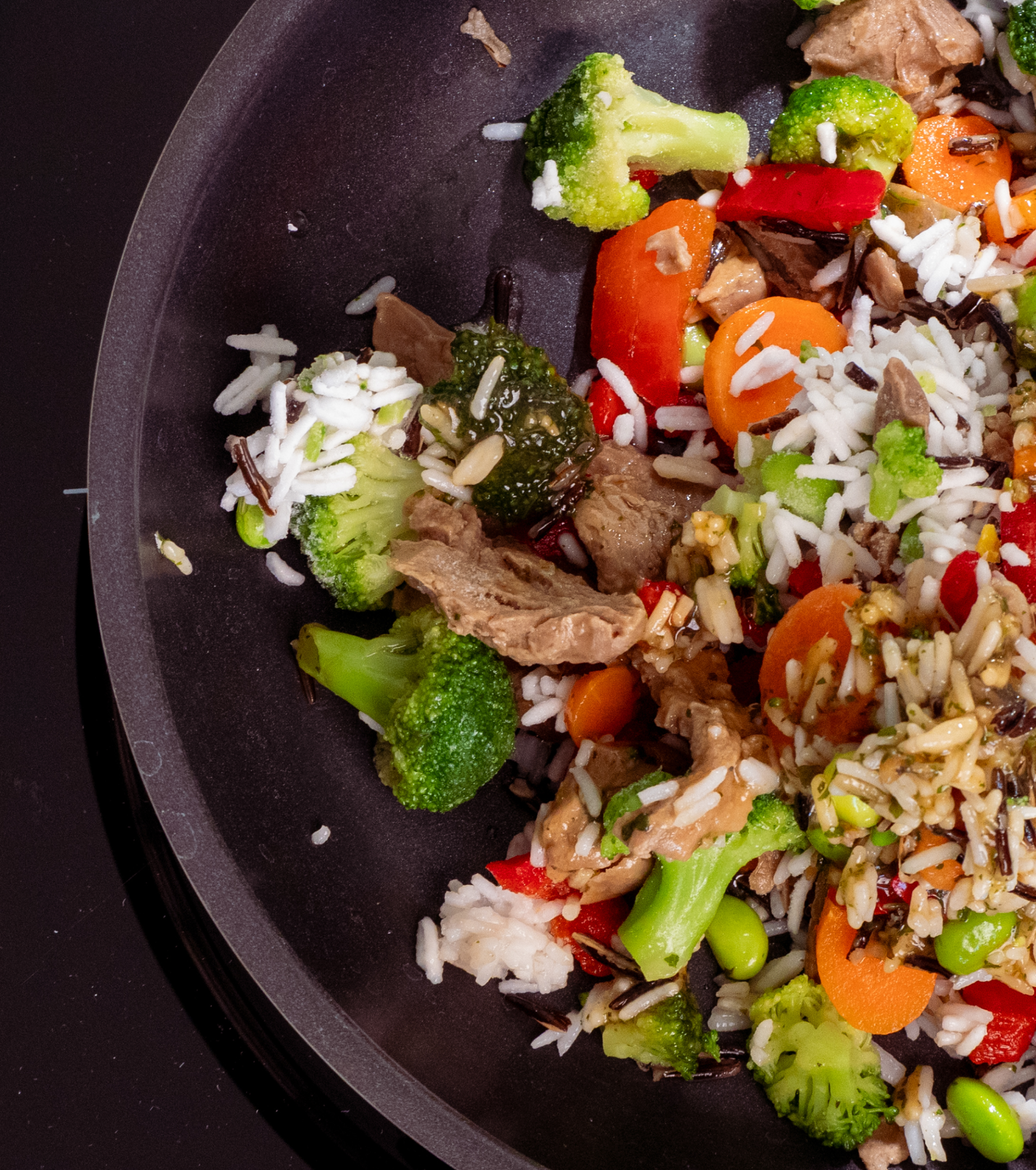 Close-up overhead shot of a finished Every Foods stir-fry with broccoli, red peppers, carrots, edamame and wild rice