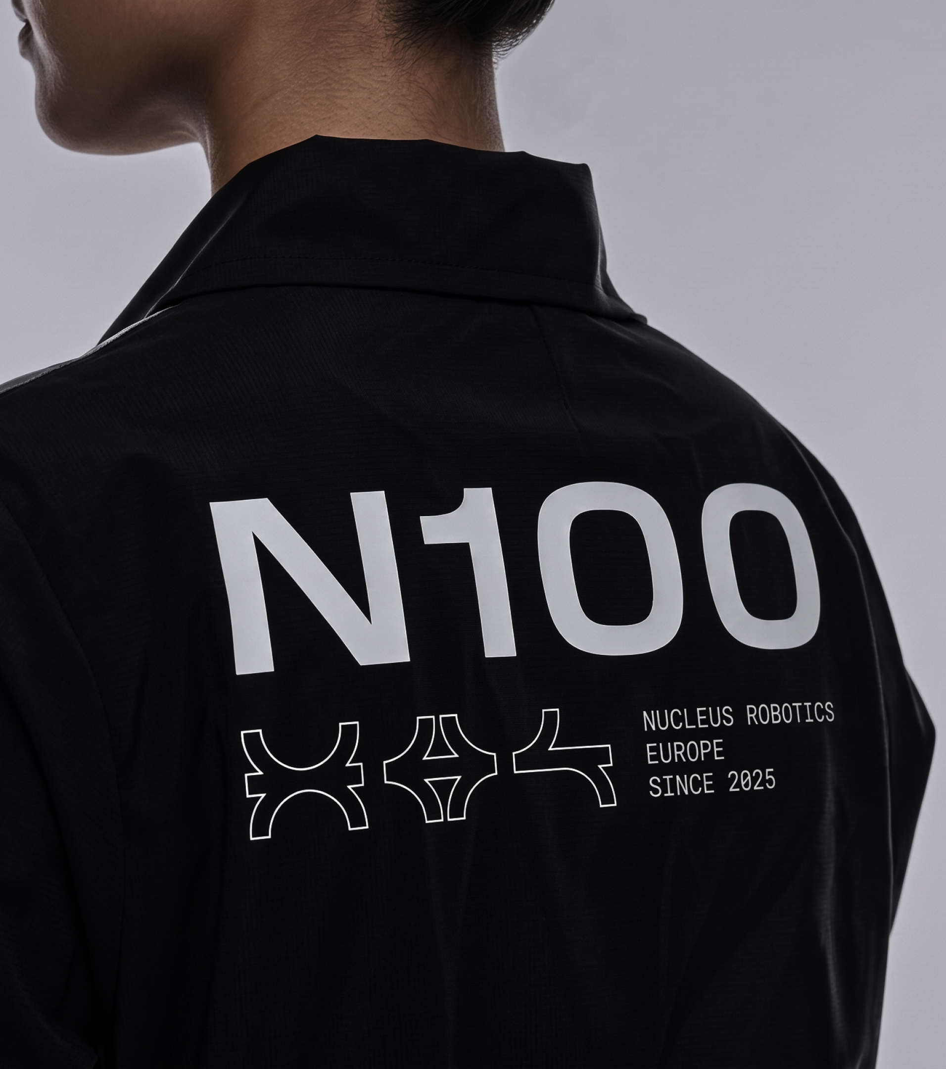Back of a black Nucleus jacket printed with "N100", the Nucleus glyphs and "Nucleus Robotics Europe Since 2025"