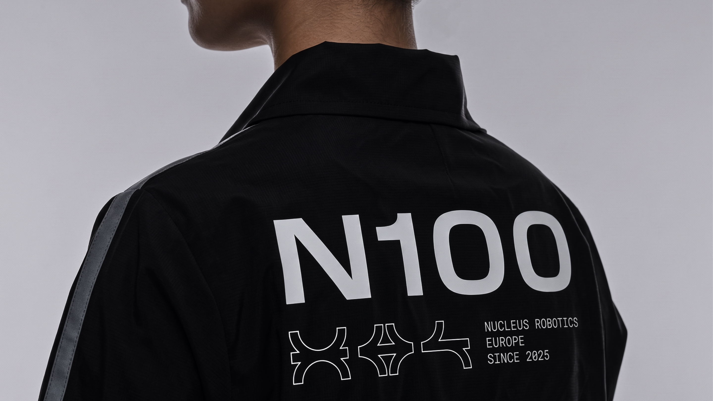 Back of a black Nucleus jacket printed with "N100", the Nucleus glyphs and "Nucleus Robotics Europe Since 2025"