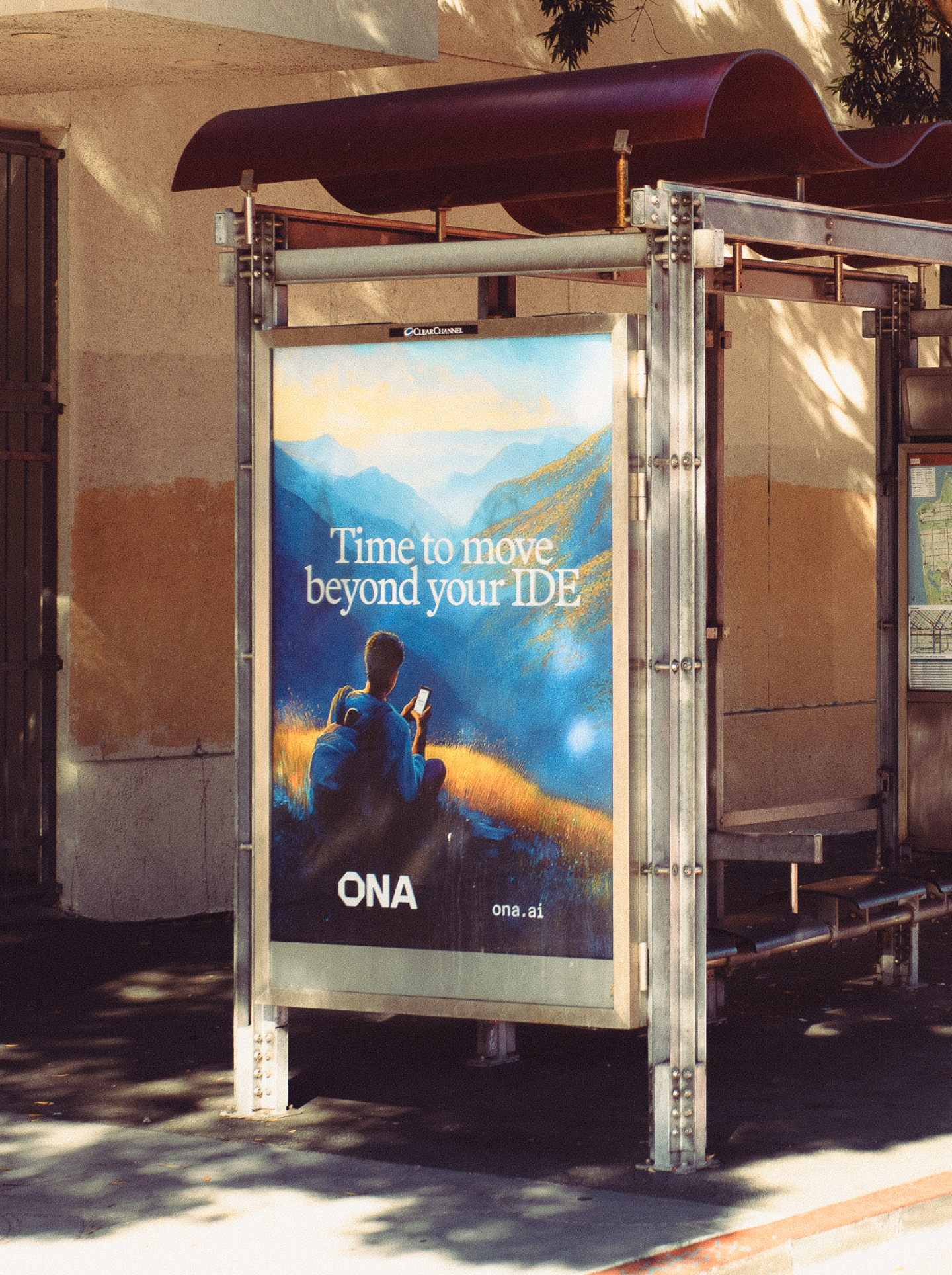 billboard at a bus stop in SF reading "Time to move beyond your IDE" with a painterly mountain landscape and the Ona logo
