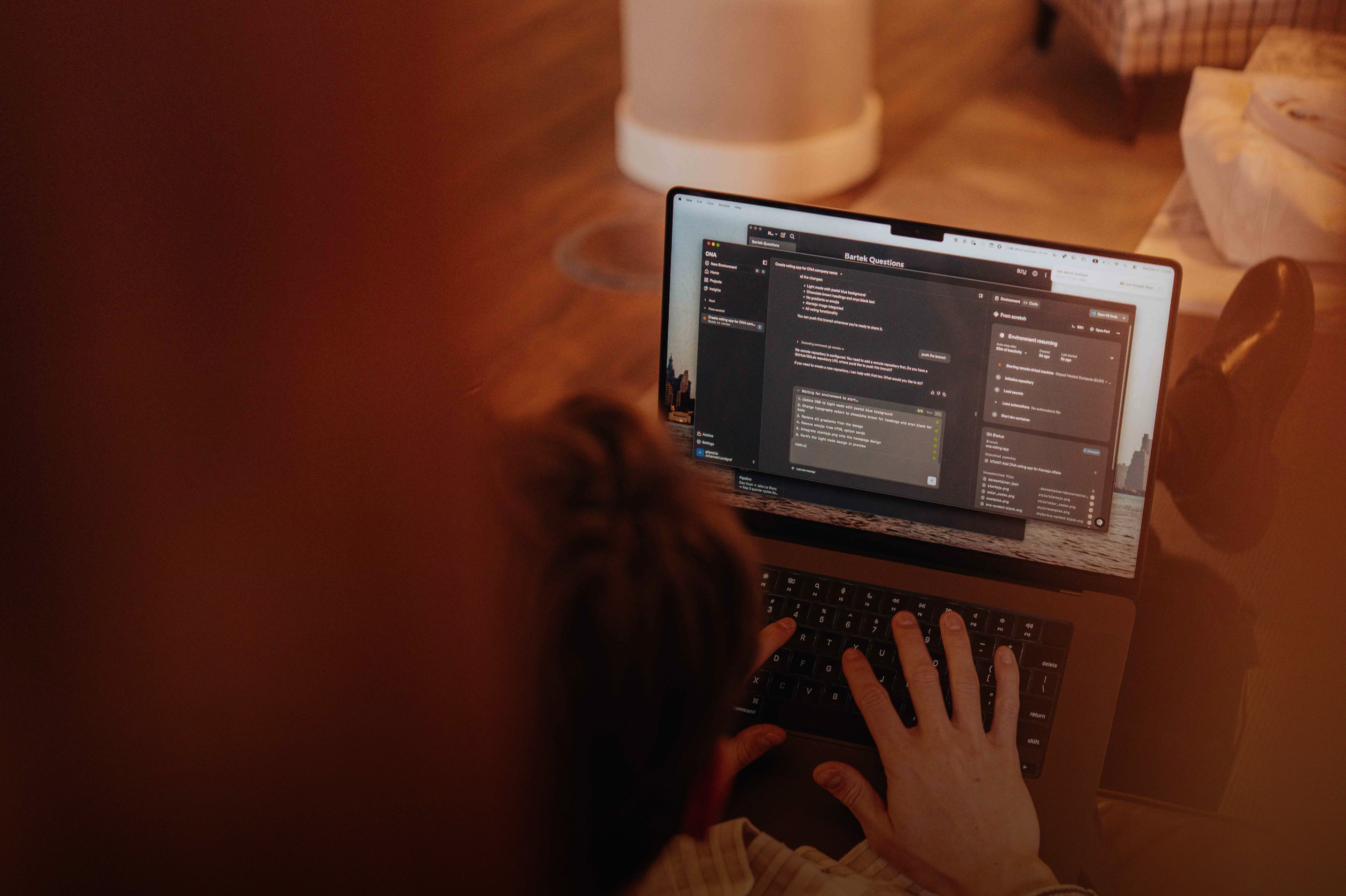 Overhead photo of a person working at a laptop in warm ambient light, the screen showing the Ona platform interface